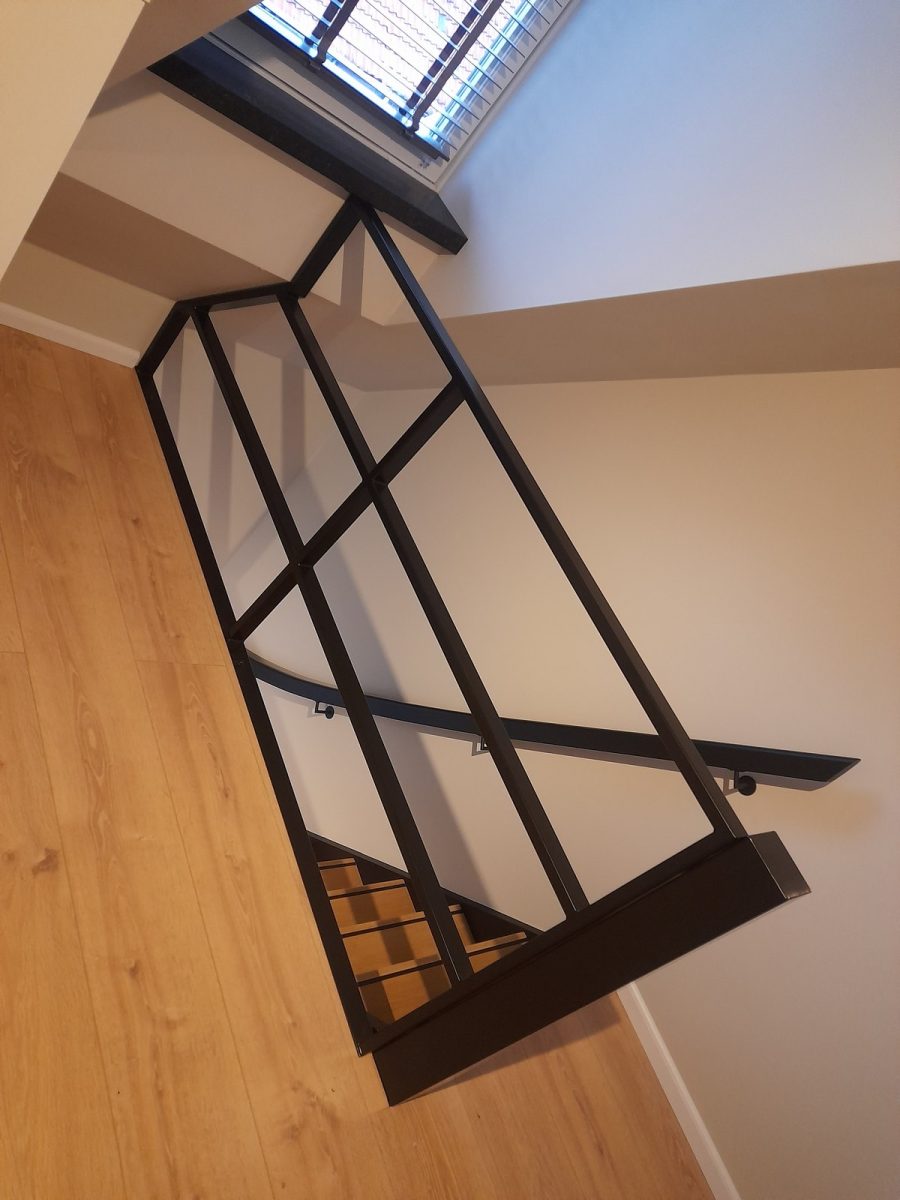 Zwarte metalen trapbalustrade en wandleuning, gezien van opzij