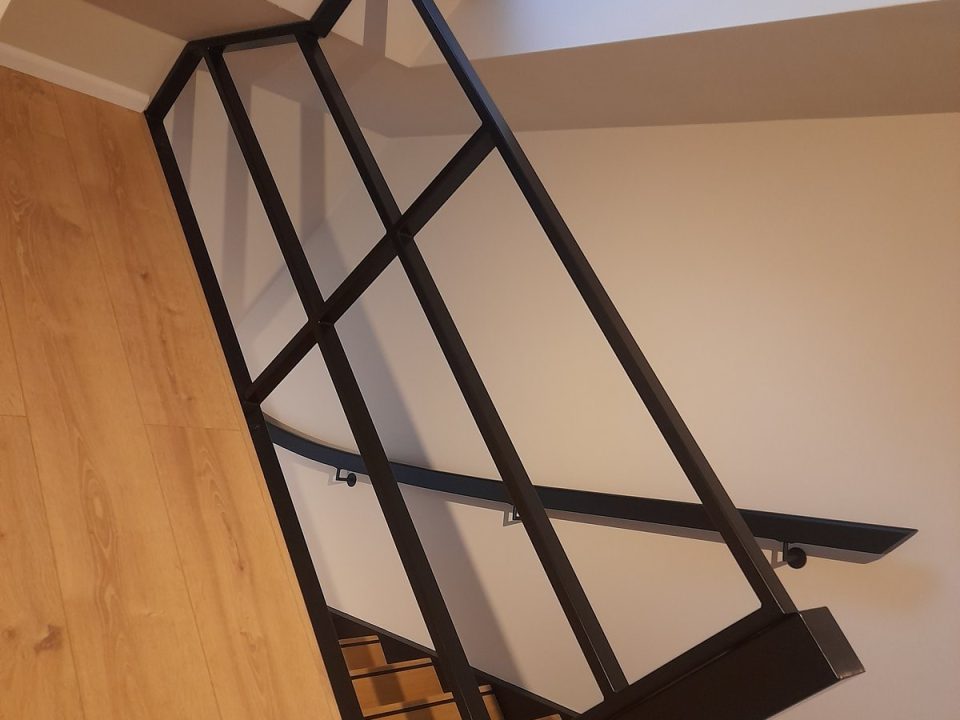 Zwarte metalen trapbalustrade en wandleuning, gezien van opzij